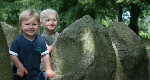 Zwei kleine Jungen verstecken sich in mitten einer Gruppe von Steindenkmälern