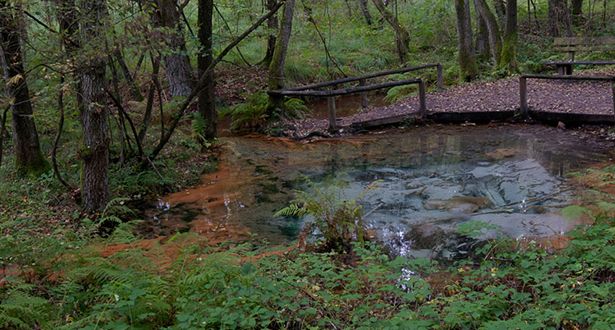 Schwindequelle mit rötlichen und türkisfarbenen Ablagerungen
