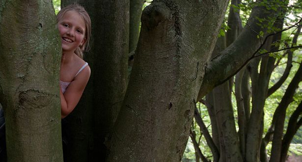 Ein kleines Mädchen versteckt sich hinter einem Baum im Marxener Paradies